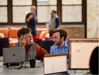 MonogramGroup Hero Photo of (Left) Partner/Creative Director, Chip Balch and (Right) Account Executive, Michael Calk discussing work business at the office.