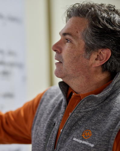 MonogramGroup Hero Photo of Partner/Creative Director, Chip Balch, writing down information he's explaining on a white board during an internal meeting at the office.