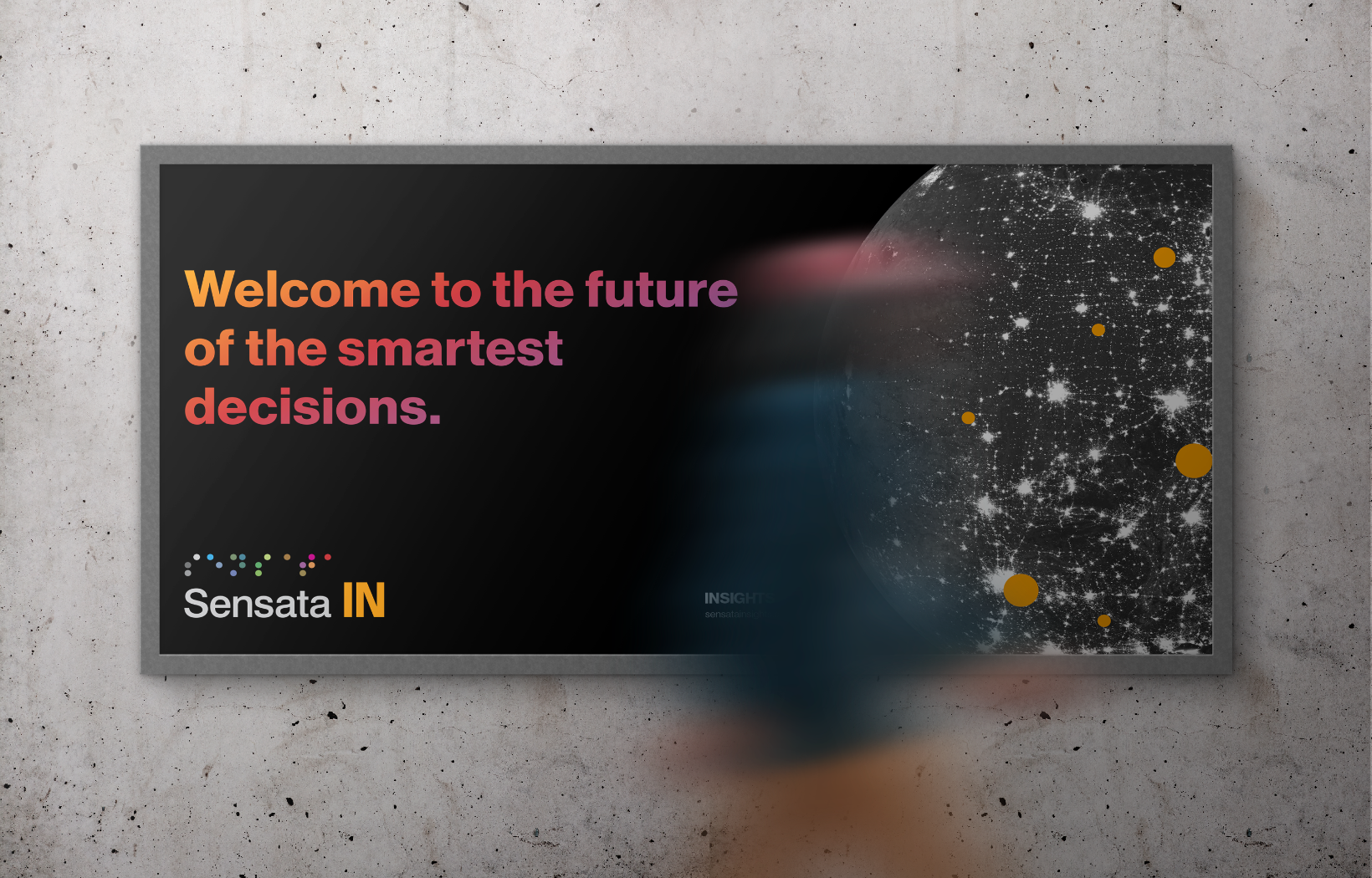 A blurred person walks past a billboard that reads, Welcome to the future of the smartest decisions. The lower section displays the logo Sensata IN with colorful dots. The background image includes a dark surface with bright flecks and circular accents.