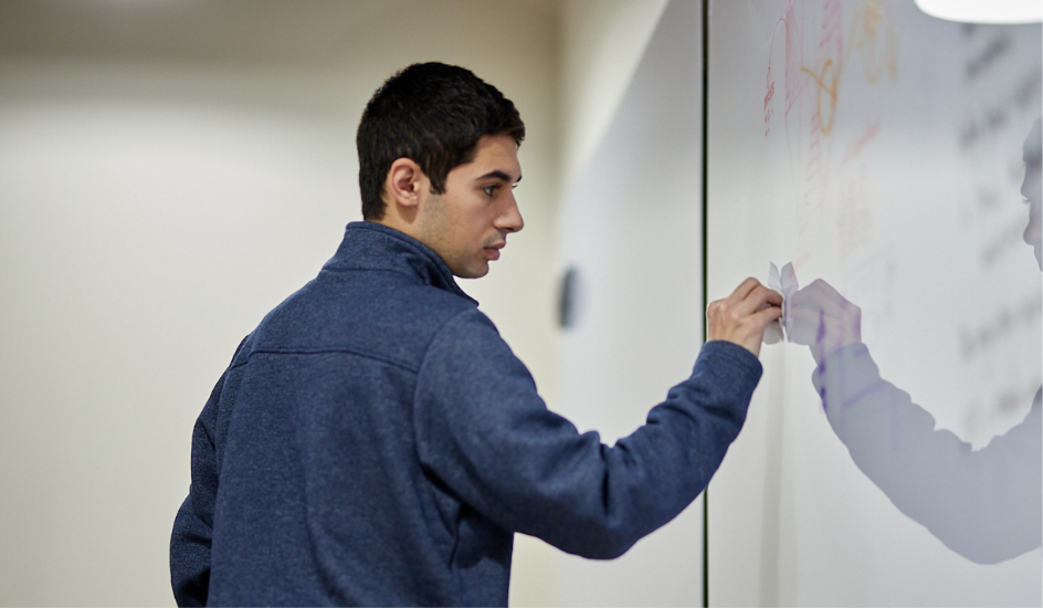 Photo of Operations Manager, Lou Petrongelli wiping off markings on a white board.