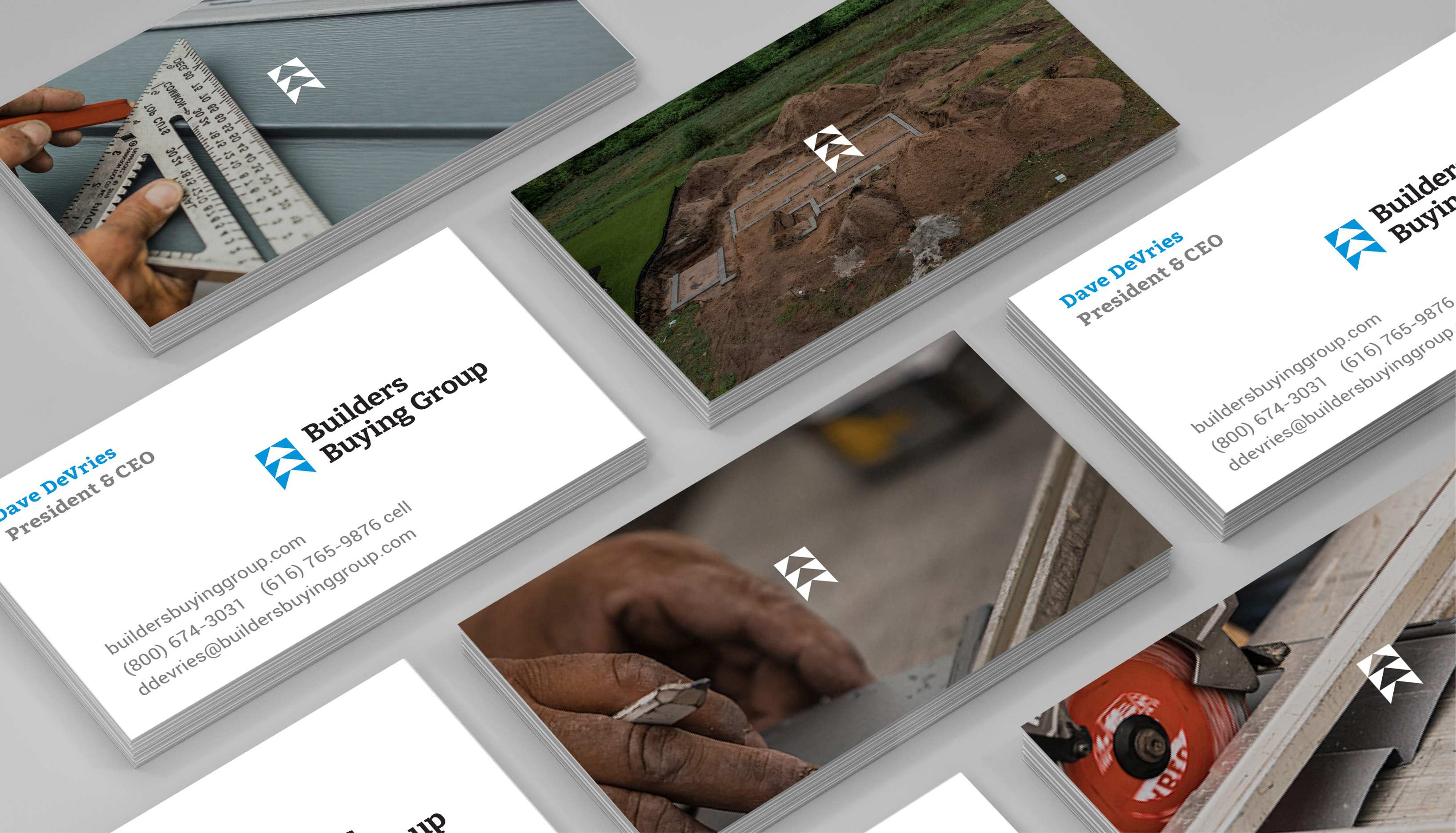 Stacks of Builders Buying Group business cards, showing contact details and the company logo. The cards lie next to images of construction tools and a building site.