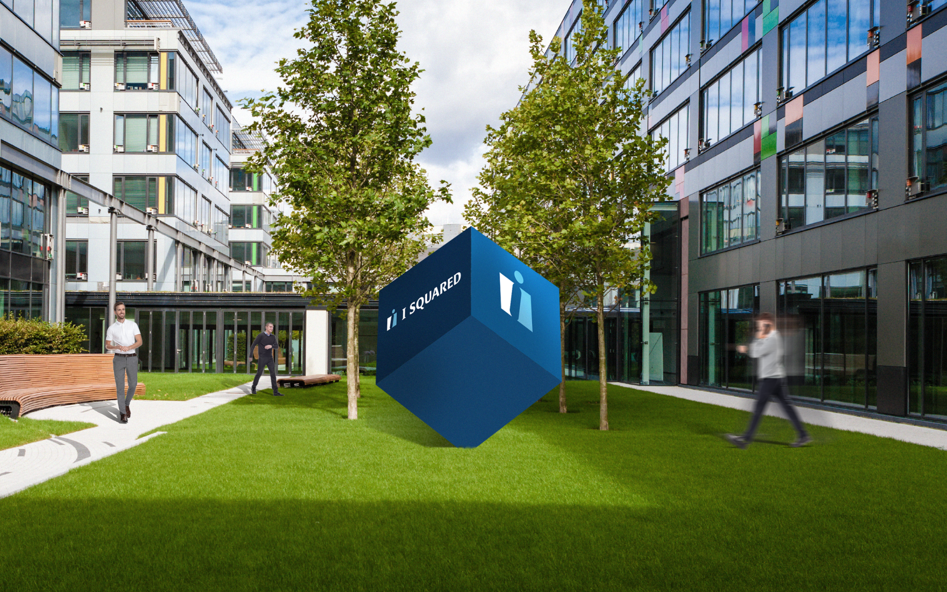 A blue cube with I SQUARED and a logo hovers on a grassy courtyard surrounded by modern buildings. Three people walk nearby, one in a white shirt and two blurred figures in motion. Tall trees and benches are present.