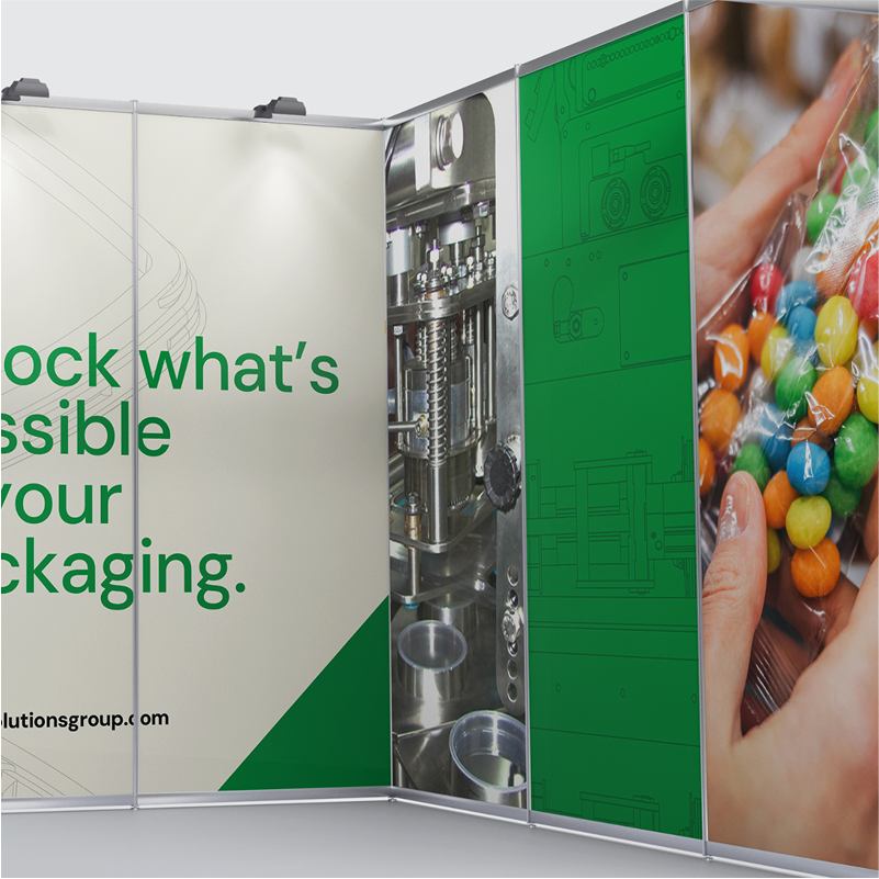 A trade show booth features text reading “Unlock what’s possible in your packaging,” a close-up of packaging machinery, and a photo of hands holding a clear bag filled with colorful candy-coated chocolates.